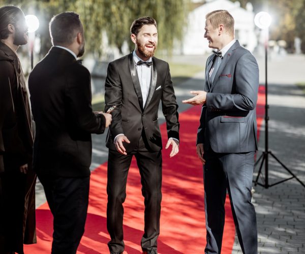 Men as a famous movie actors gathering together and greeting each other on the red carpet at the awards ceremony outdoors